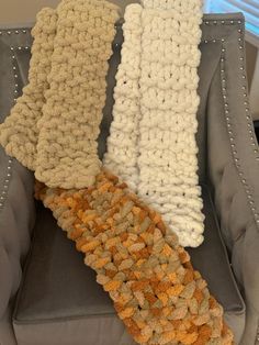 two crocheted scarves sitting on top of a gray chair