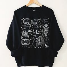 This Dark Academia Halloween Shirt has a retro vibe with fun spooky season graphics. You will want to wear this cute Fall shirt on repeat.  This is a relaxed fit unisex sweatshirt, but true to size. We recommend sizing up if you want a trendy oversized look. - M A T E R I A L S - Gildan® Sweatshirt 8 oz./yd² (US) 50/50 cotton/polyester Heather Sport colors: 60/40 polyester/cotton Loose Fit Ribbed Knit Collar to retain shape - C A R E  I N S T R U C T I O N S - Inside out, wash with delicate cycl Black Halloween Graphic Print Sweatshirt, Spooky Black T-shirt For Winter, Black Grunge Sweatshirt For Halloween, Spooky Skull Print Top For Fall, Spooky Skull Print Fall Top, Spooky Skull Print Tops For Fall, Halloween Long Sleeve Screen Print Tops, Long Sleeve Halloween Screen Print Tops, Long Sleeve Screen Print Tops For Halloween