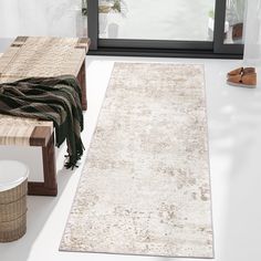 a white rug sitting on top of a floor next to a wooden bench and window