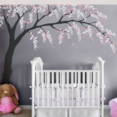 a baby's room with a tree painted on the wall