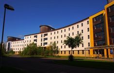 the building is white and yellow with many windows on each side, along with green grass