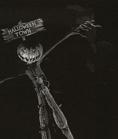 a scarecrow holding a sign that says halloween town