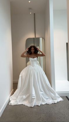 a woman in a white wedding dress standing by a mirror