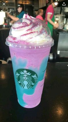 a pink and blue drink sitting on top of a table next to a person in the background