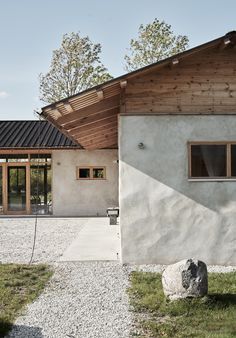 the house is made out of concrete and has a large rock in front of it