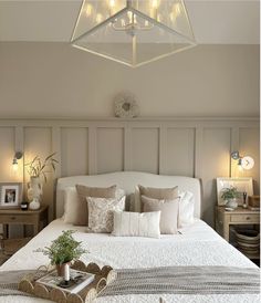 a white bed sitting under a light fixture in a bedroom