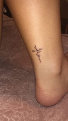 a woman's foot with a cross tattoo on it