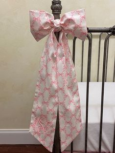 a pink and white bow tie on top of a crib