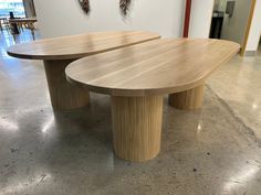 two circular wooden tables sitting on top of a cement floor next to each other in an office