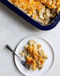 a white plate topped with macaroni and cheese next to a blue casserole dish