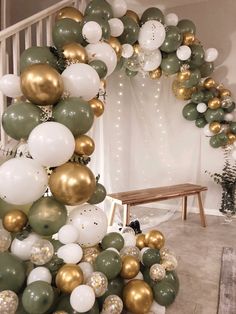 a bunch of balloons that are in the shape of a christmas tree with gold, white and green decorations