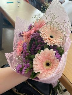 a bouquet of pink and purple flowers in someone's hand