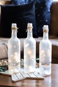 three bottles with lights in them sitting on a table