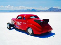 an old red car is parked in the desert