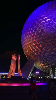 the spaceship shaped building is lit up with purple and blue lights in front of it