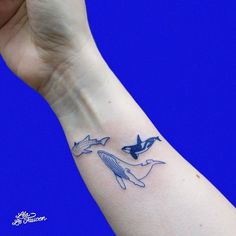 a person's arm with a tattoo on it and two dolphins swimming in the water