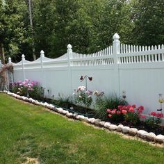 a white picket fence with pink flowers in the foreground