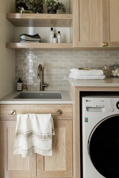 a washer and dryer in a small room with wooden cabinets, white tile backsplash