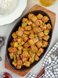 a pan filled with tofu and vegetables next to rice