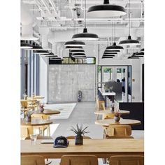 the interior of a restaurant with wooden tables and chairs, hanging lights, and potted plants