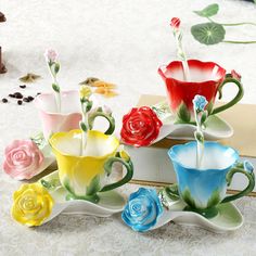 four coffee cups with flower designs on them sitting on a table next to a book