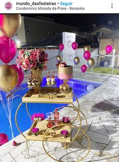 a table that has some food on it near a pool with pink and gold balloons