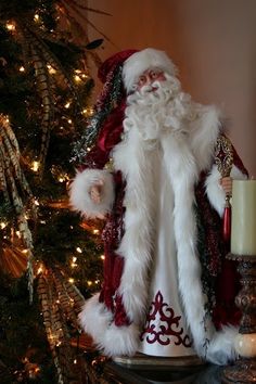 a santa clause figurine sitting on top of a table next to a christmas tree