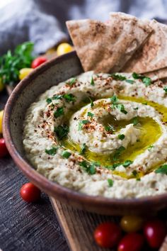 hummus in a bowl with pita chips and cherry tomatoes on the side for garnish