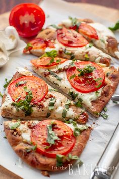 several slices of pizza on a cutting board with tomatoes and herbs next to the knife