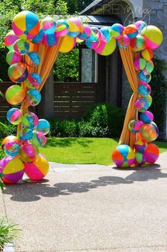 an arch decorated with balloons and streamers for a party or wedding ceremony in the backyard