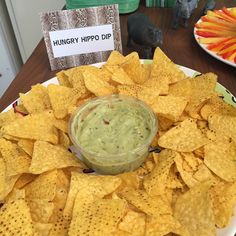 a white plate topped with chips and guacamole next to a sign that says hungry hipo dip