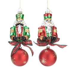 two christmas ornaments hanging from strings on a white background, each with a santa clause ornament