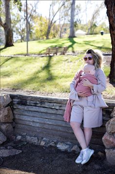 a woman holding a baby in her arms while sitting on a stone bench next to a tree