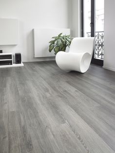 a white chair sitting on top of a hard wood floor next to a fire place