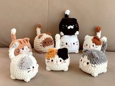 several crocheted cats sitting on top of a couch with one cat in the middle