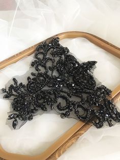 a piece of black beaded fabric sitting on top of a wooden frame