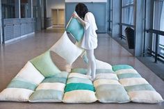 a woman standing on top of a pile of pillows in the middle of a room