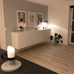 a living room with pictures on the wall and a candle in front of an end table