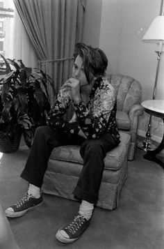 a man sitting on top of a couch in a living room next to a plant