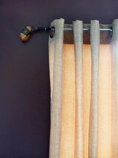 the curtain is hanging on the wall next to the window with an old fashioned wooden handle