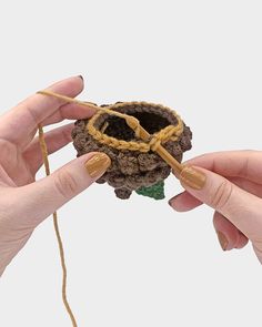 two hands are holding an object made out of yarn and rope, which is shaped like a flower