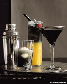 three cocktails and two shakers sit on a table next to eachother