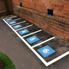 an empty parking lot with blue and white signs on the ground next to a brick wall