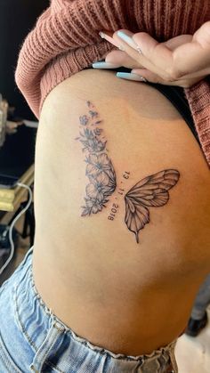 a woman's stomach with a butterfly tattoo on her belly and flowers in the back