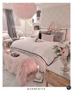 a bedroom decorated in white and pink with lots of pillows on the bed, lights hanging from the ceiling