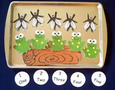 a tray that has some cut outs in front of it with four green frogs on it