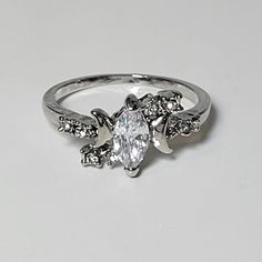 a white gold ring with an oval cut diamond surrounded by smaller round diamonds on each side