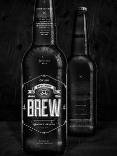 two bottles of beer sitting next to each other on top of a wooden table in black and white