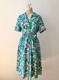 "Adorable cotton shirtdress from the 1950's with a fantastic floral print.  This vibrant number is made of super soft, medium weight cotton and features a button up front, tie belt and side hip seam pockets.  In perfect condition with no flaws to note, clean and ready to wear.  ~ Measurements ~  Bust: 42\"- 44\" snug (might cause some gaping between the buttons at 44\") Waist: 36\" Hip: open" Cotton Button-up Shirt Dress With Floral Print, Floral Print Cotton Button-up Shirt Dress, Cotton Floral Print Button-up Shirt Dress, Cotton Floral Print Short Sleeve Shirt Dress, Cotton Short Sleeve Shirt Dress With Floral Print, Cotton Floral Print Shirt Dress With Short Sleeves, Retro Button-up Floral Print Dress, Retro Floral Print Button-up Dresses, Vintage Collared Floral Print Dress