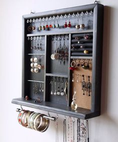 a wall mounted jewelry organizer with lots of earrings